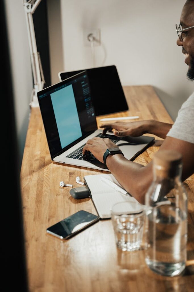 Adult man working on a laptop at home office with a modern setup.